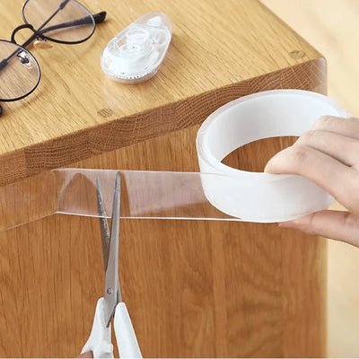 Doppelseitiges, transparentes Klebeband, das mit einer Schere auf einer Holzoberfläche zugeschnitten wird.