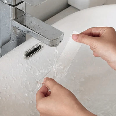 Hände waschen ein Stück transparentes, doppelseitiges Klebeband unter fließendem Wasser im Waschbecken.