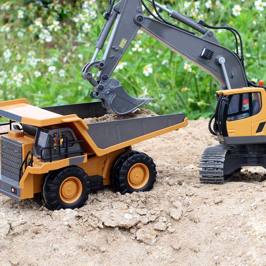 Ein ferngesteuerter Bagger lädt Sand auf einen Muldenkipper in einer Gartenumgebung.