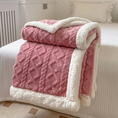 Eine rosa Fleecedecke mit Lammwolle-Optik, die gefaltet auf einem weißen Bett liegt.