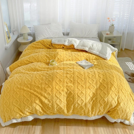 Gelbe Fleecedecke mit Lammwolle auf einem Bett in einem hellen Schlafzimmer