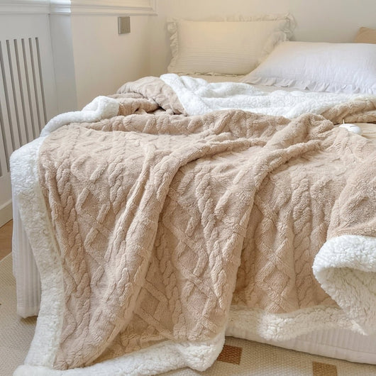 Eine beidseitige Fleecedecke mit Lammwolle in Beige und Weiß, die gemütlich auf einem Bett ausgebreitet ist.