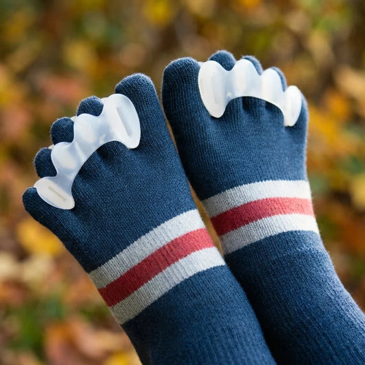 Hammerzehenkorrektor aus Silikongel zur Begradigung und Druckentlastung, getragen in blauen Zehensocken.