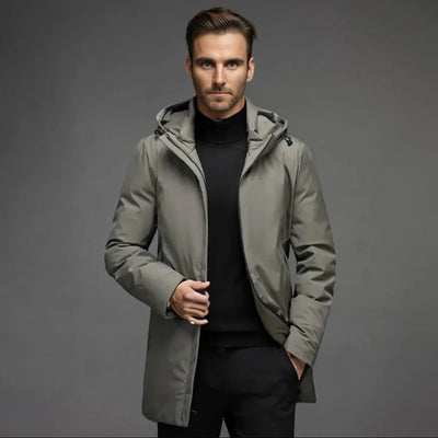 Ein Mann trägt einen wasserdichten, gefütterten Winterparka in Grau über einem schwarzen Rollkragenpullover.