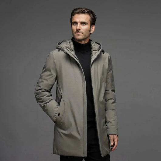 Ein Mann trägt einen wasserdichten, gefütterten Winterparka in Grau mit Kapuze und schwarzem Rollkragenpullover.