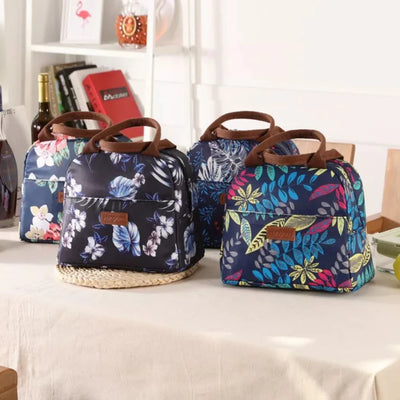 Vier kleine, isolierte Kühltaschen mit verschiedenen Blumenmustern auf einem Tisch.