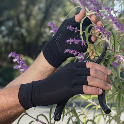 Person trägt Kupferkompressionshandschuhe mit offenen Fingern bei der Gartenarbeit mit einer Gartenschere.