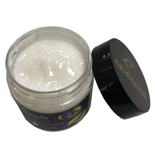 Ein offener Tiegel mit weißer Lederpflegecreme und daneben liegendem schwarzen Deckel mit Eidechsen-Logo.