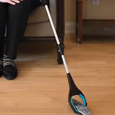 Ein faltbarer Greifer mit 81 cm Länge und drehbarem Kopf hebt eine Fernbedienung vom Boden auf.