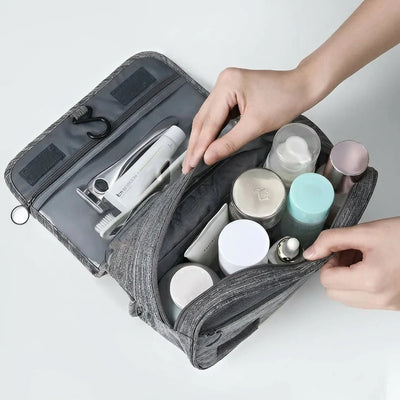 Eine offene, wasserabweisende Kosmetiktasche für Herren mit verschiedenen Pflegeprodukten, die zum Aufhängen geeignet ist.