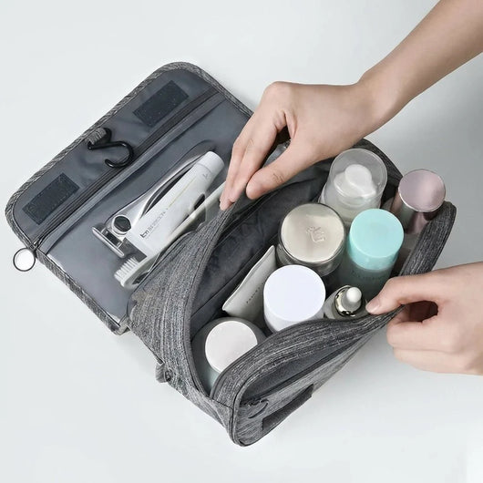 Eine offene, wasserabweisende Kosmetiktasche für Herren mit verschiedenen Pflegeprodukten, die zum Aufhängen geeignet ist.