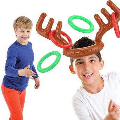 Zwei Kinder spielen Ringwerfen mit einem aufblasbaren Rentiergeweih als Kopfschmuck.