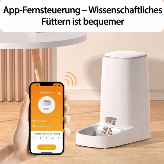 Hand hält ein Smartphone mit App-Steuerung für einen automatischen Katzenfutterspender, der Futter in eine Schale ausgibt.