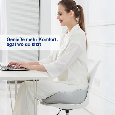 Eine Frau sitzt auf einem ergonomischen Memory-Schaum-Sitzkissen an einem Schreibtisch.